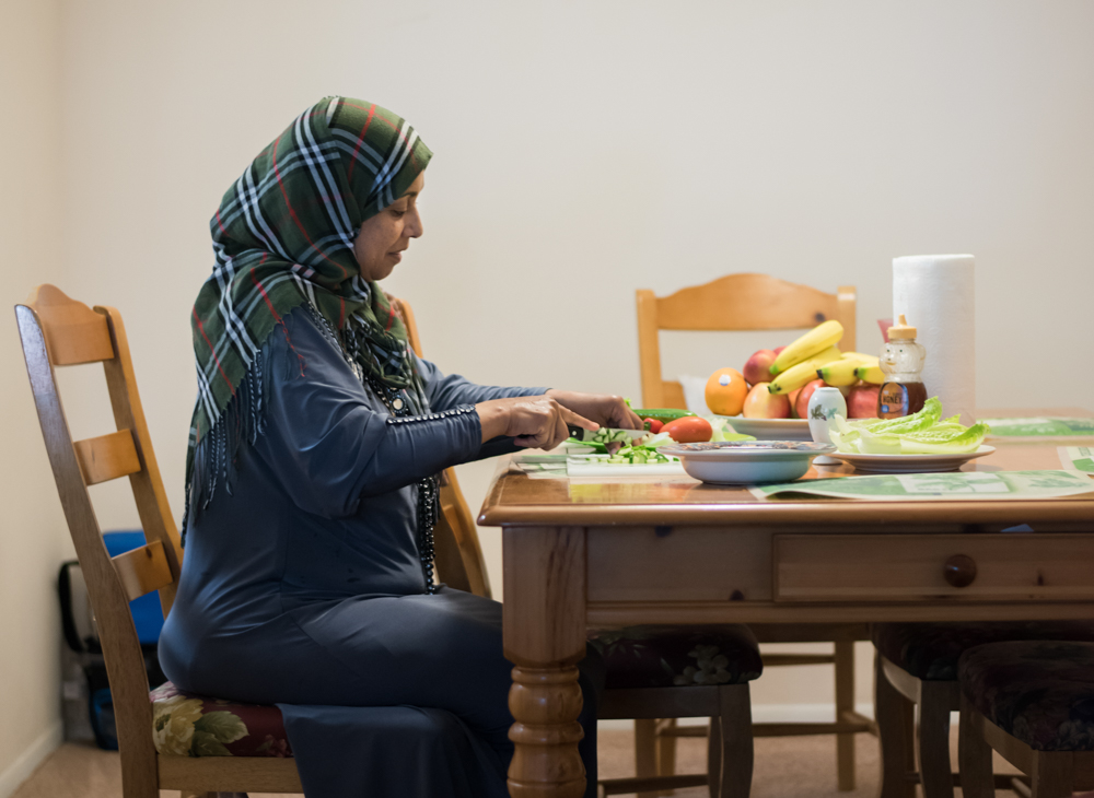 Refugee mother at the table cutting vegetables for her familys lunch in jacksonville Florida