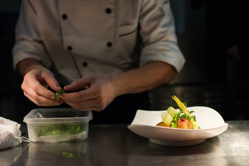 chef hands placing final garnishes on a plate at Blackfly Restaurant