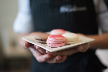 one pink macaron held in hands on a white plate at matthews restaurant in jacksonville florida