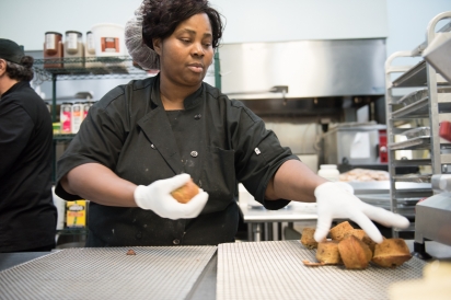 Food service worker moving fresh baked muffins