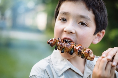 boy eating chicken skewer