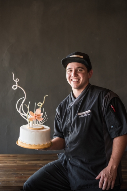 Nils Rowland pastry chef at Creme de la cocoa sits on table with sugar cake sculpture