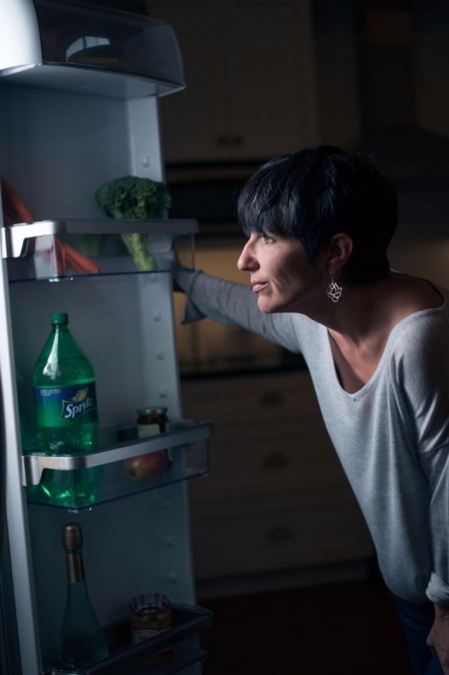 Woman standing by fridge choosing food