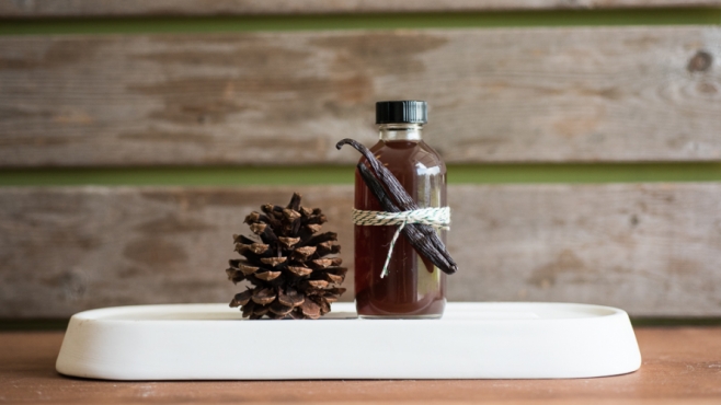 Vanilla extract with a wood slatted background and pinecone