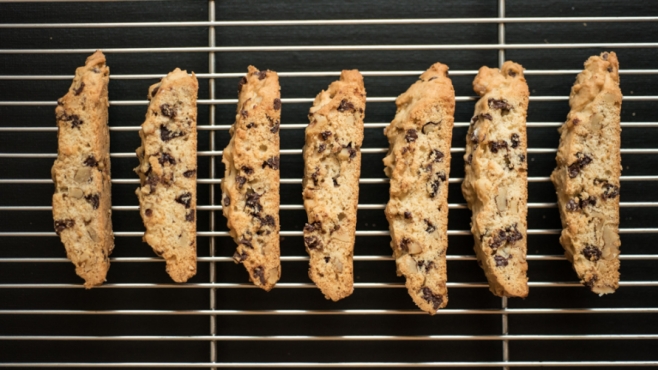 Chocolate Chip walnut biscotti on a baking rack with black background