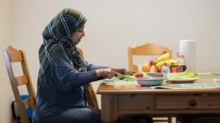 Refugee mother at the table cutting vegetables for her familys lunch in jacksonville Florida