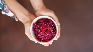 beet kimchi in white bowl in palm of hands